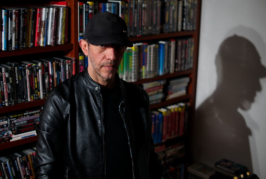 Uomo con libreria alle spalle piena di musicassette